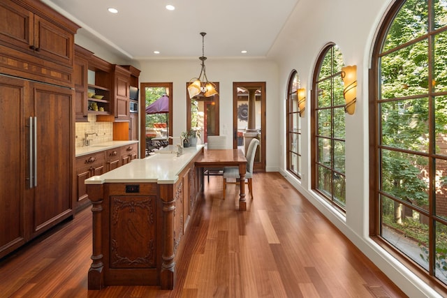 kitchen with tasteful backsplash, paneled built in refrigerator, dark hardwood / wood-style flooring, a notable chandelier, and hanging light fixtures