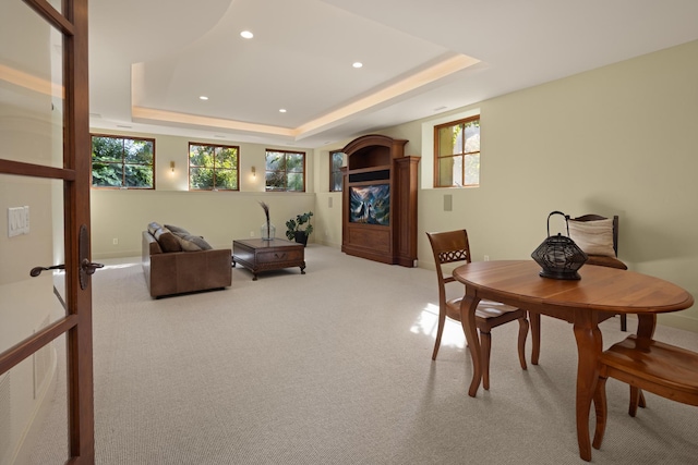 carpeted dining space with a raised ceiling