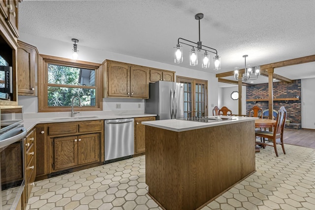 kitchen with a kitchen island, sink, pendant lighting, appliances with stainless steel finishes, and a textured ceiling