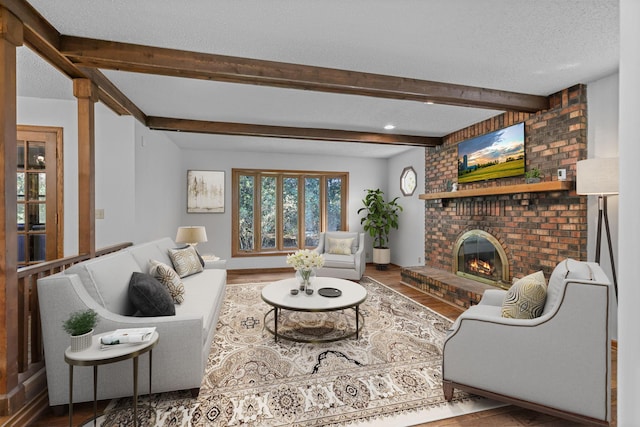 living room featuring beamed ceiling, a textured ceiling, a fireplace, and wood-type flooring