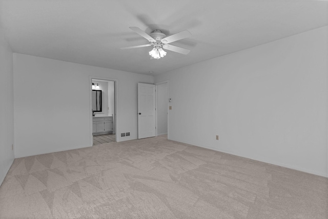 unfurnished bedroom featuring ceiling fan, light carpet, and ensuite bathroom