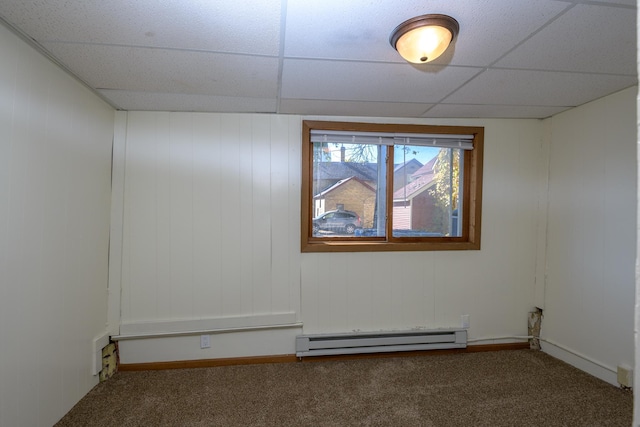 empty room featuring a paneled ceiling, carpet flooring, and a baseboard radiator