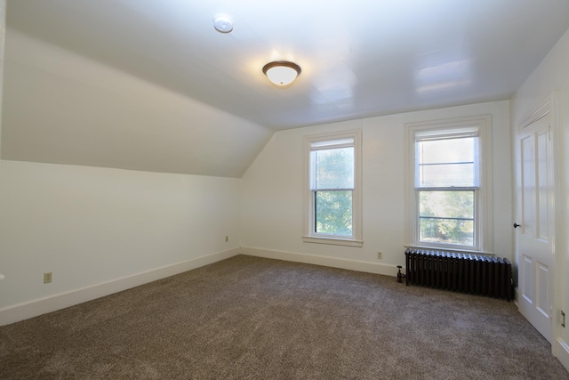 bonus room with dark colored carpet, radiator heating unit, and lofted ceiling