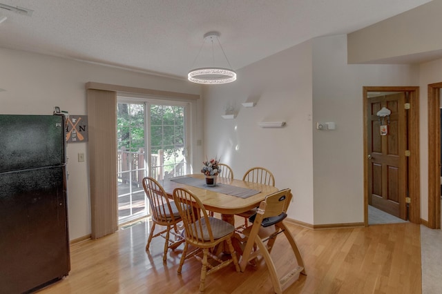 dining space featuring light wood-type flooring and a textured ceiling