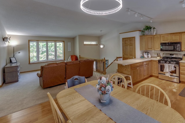 dining space featuring track lighting, light wood-type flooring, and vaulted ceiling