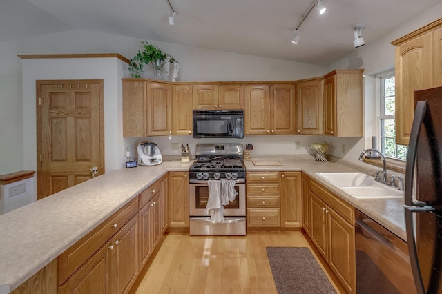 kitchen featuring vaulted ceiling, sink, stainless steel appliances, and track lighting