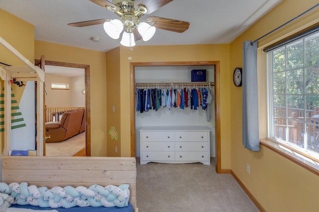 carpeted bedroom with ceiling fan and a closet