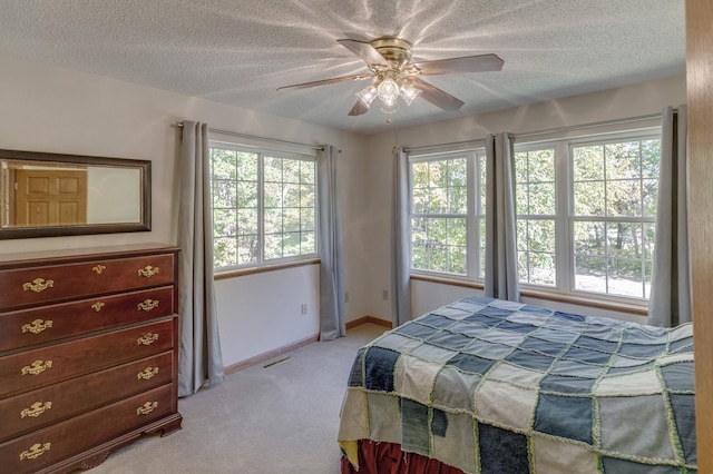 bedroom with multiple windows, ceiling fan, and light carpet