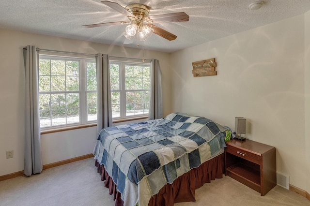 carpeted bedroom with a textured ceiling, multiple windows, and ceiling fan