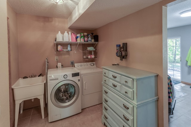 clothes washing area featuring washing machine and clothes dryer, light tile patterned floors, and a textured ceiling