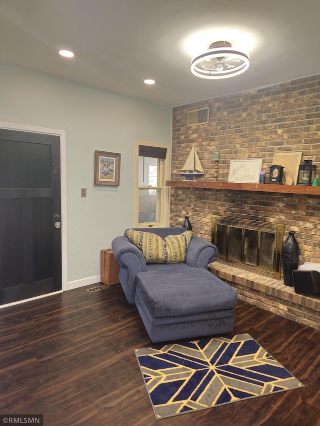 living room featuring brick wall, dark hardwood / wood-style floors, and a fireplace