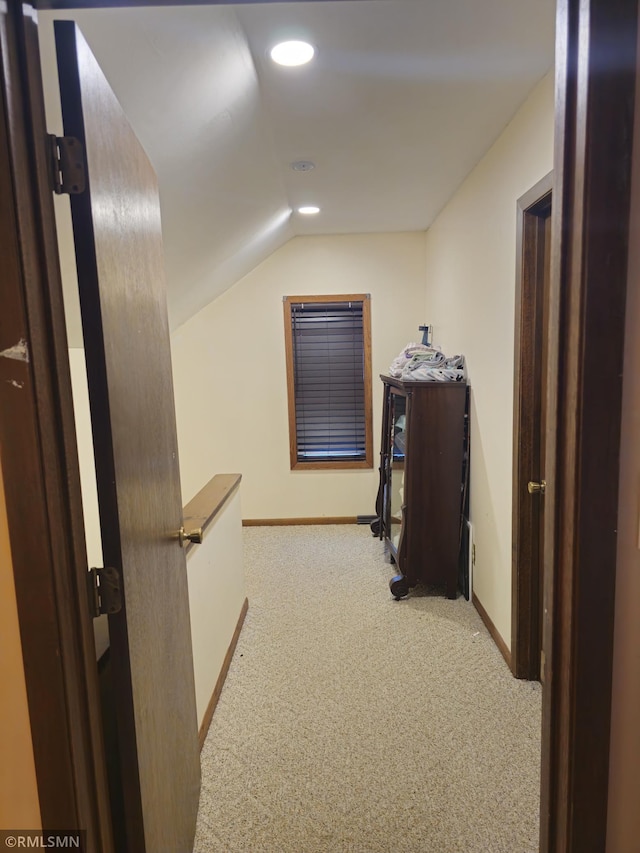 corridor featuring vaulted ceiling and light carpet