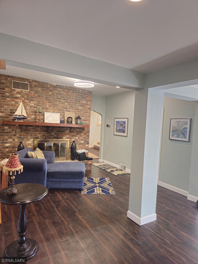 living room with dark hardwood / wood-style floors and brick wall