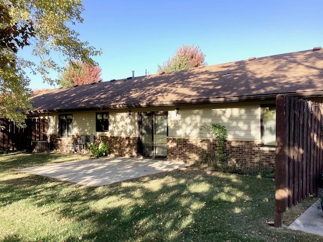 view of front facade featuring roof with shingles, a front yard, a patio, and brick siding