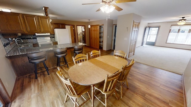 dining space with ceiling fan, baseboards, and light wood-type flooring