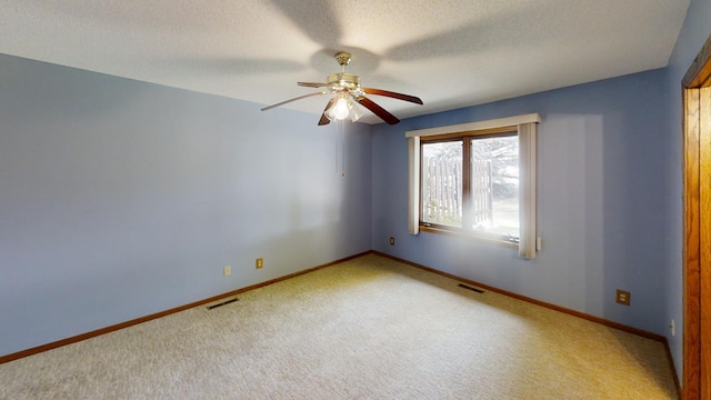 empty room featuring light carpet, ceiling fan, and a textured ceiling