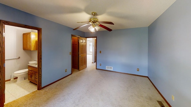 unfurnished bedroom featuring light colored carpet, ceiling fan, connected bathroom, and a textured ceiling