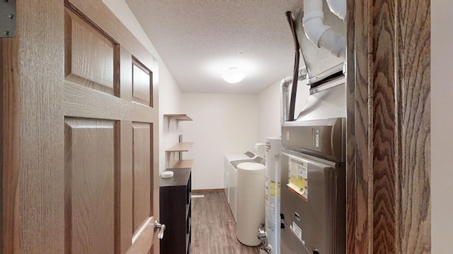 laundry room featuring stacked washer / dryer, hardwood / wood-style floors, and a textured ceiling