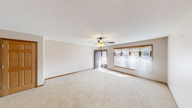 spare room with ceiling fan, light colored carpet, and a textured ceiling