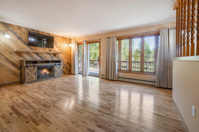 unfurnished living room with a baseboard radiator, wooden walls, and hardwood / wood-style flooring