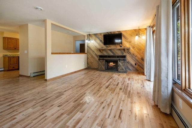 unfurnished living room with light hardwood / wood-style flooring, a baseboard heating unit, and a notable chandelier