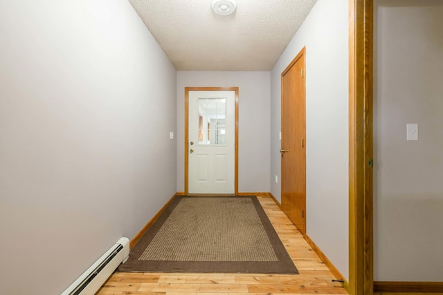 doorway to outside featuring a textured ceiling, light wood-type flooring, and baseboard heating