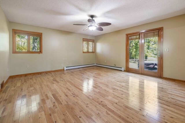 spare room featuring a textured ceiling, light hardwood / wood-style flooring, and a baseboard radiator