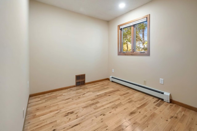 empty room featuring baseboard heating and light hardwood / wood-style flooring