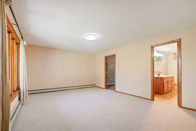 unfurnished bedroom with light colored carpet, sink, baseboard heating, and ensuite bathroom