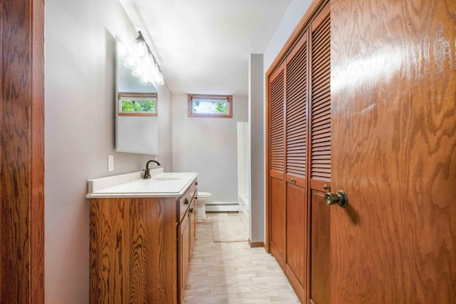 bathroom featuring vanity, toilet, a baseboard heating unit, and hardwood / wood-style flooring