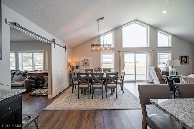 dining area featuring a barn door, high vaulted ceiling, dark hardwood / wood-style flooring, and a wealth of natural light