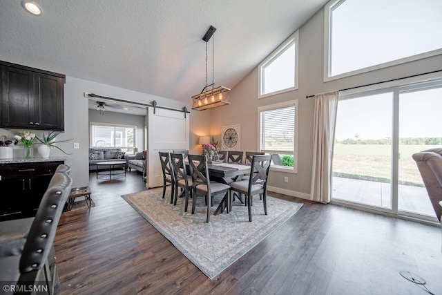 dining space with a barn door, plenty of natural light, dark hardwood / wood-style flooring, and ceiling fan