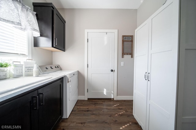 laundry room featuring washing machine and clothes dryer, cabinets, and dark hardwood / wood-style flooring