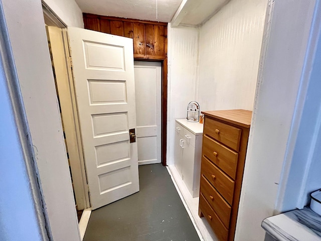 bathroom featuring wood walls, concrete floors, and toilet