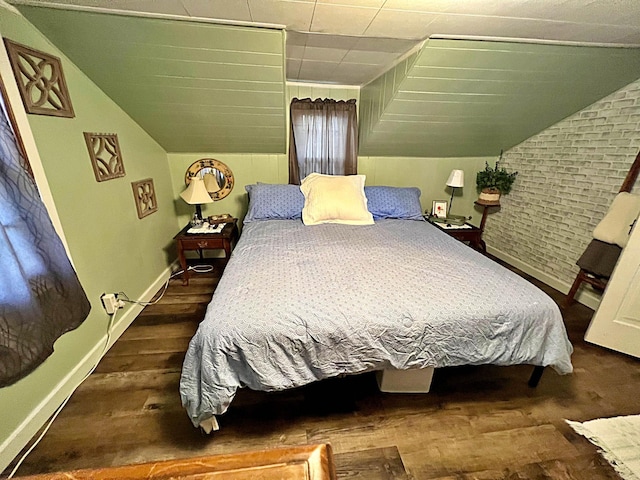 bedroom featuring brick wall, dark hardwood / wood-style floors, and vaulted ceiling