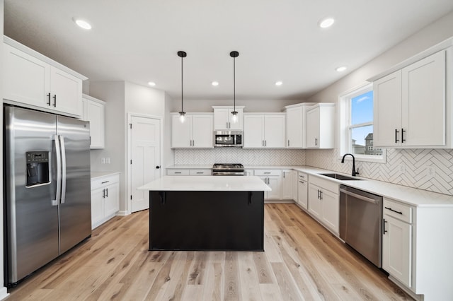 kitchen featuring sink, hanging light fixtures, appliances with stainless steel finishes, a kitchen island, and white cabinets