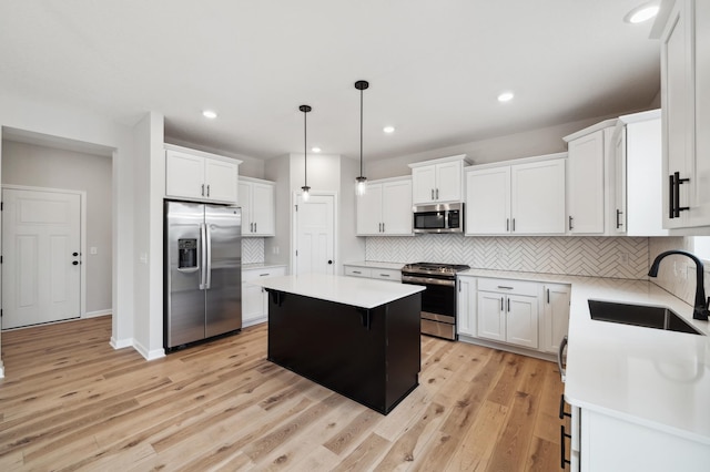 kitchen featuring sink, white cabinetry, appliances with stainless steel finishes, a kitchen island, and pendant lighting