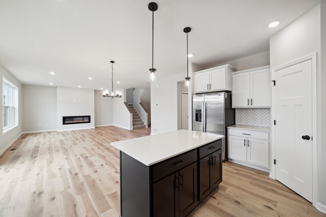 kitchen featuring white cabinetry, backsplash, pendant lighting, and light wood-type flooring