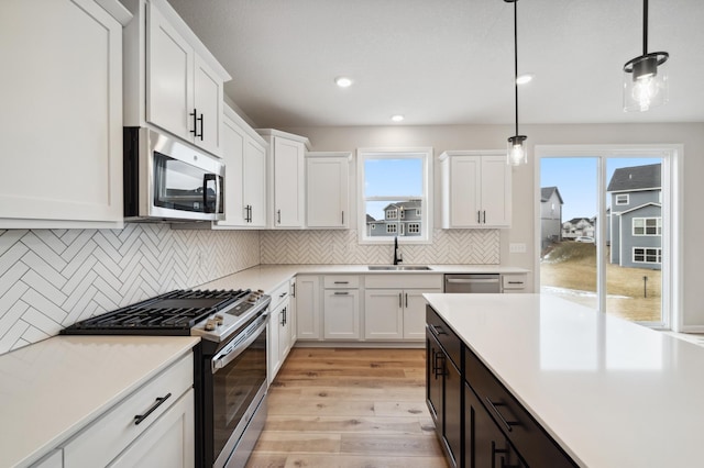 kitchen with white cabinetry, appliances with stainless steel finishes, sink, and pendant lighting