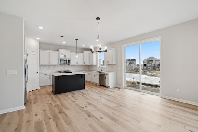 kitchen with a kitchen island, tasteful backsplash, white cabinets, hanging light fixtures, and stainless steel appliances