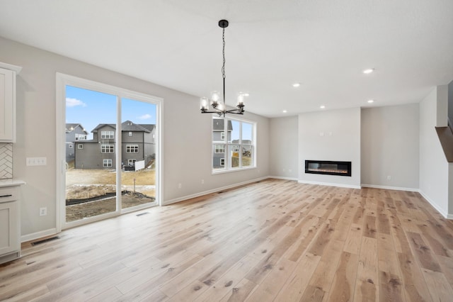 unfurnished living room with a notable chandelier and light hardwood / wood-style flooring