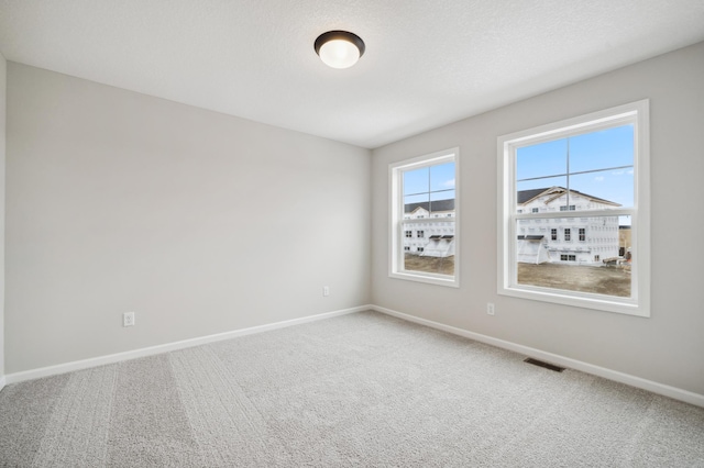 carpeted spare room with a textured ceiling