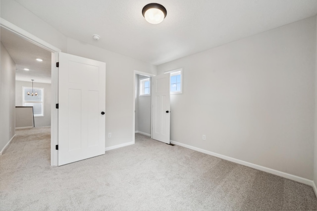 unfurnished bedroom featuring an inviting chandelier and light colored carpet