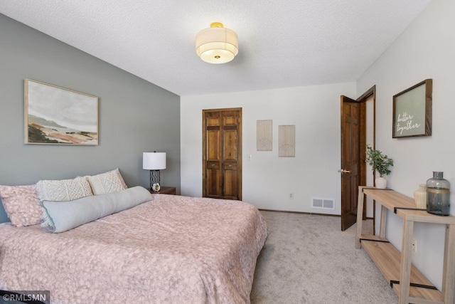 bedroom featuring a textured ceiling, light carpet, visible vents, and baseboards