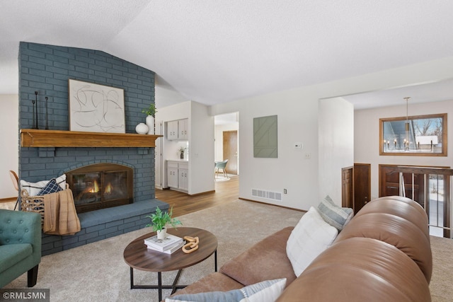 living room featuring lofted ceiling, carpet floors, a fireplace, visible vents, and baseboards