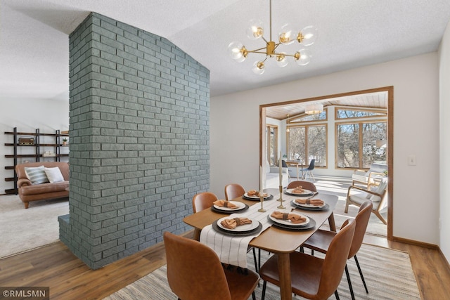 dining room featuring brick wall, vaulted ceiling, a textured ceiling, light wood-type flooring, and a notable chandelier