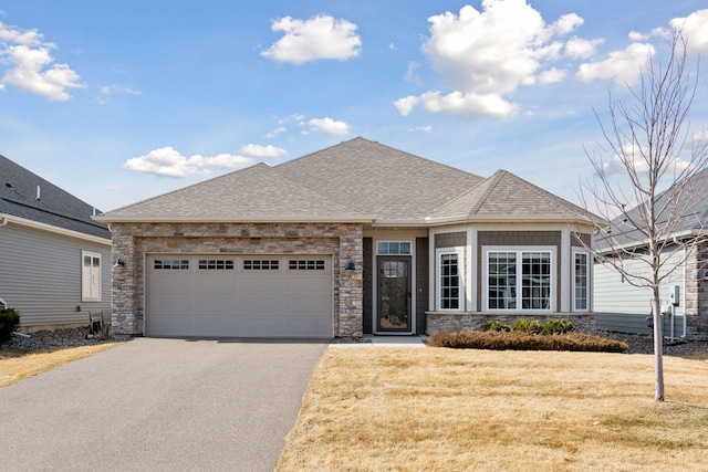 view of front facade featuring a front lawn, aphalt driveway, roof with shingles, a garage, and stone siding