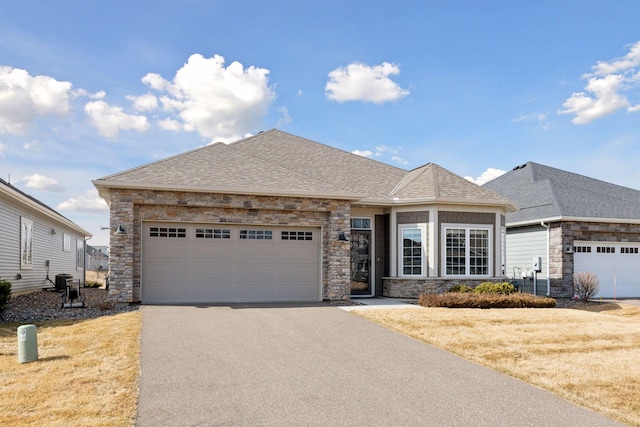 view of front of home with aphalt driveway, stone siding, a garage, and roof with shingles