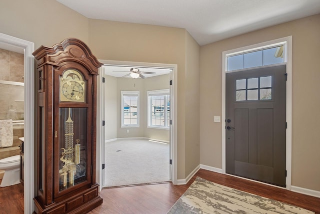 foyer entrance with a ceiling fan, baseboards, and wood finished floors