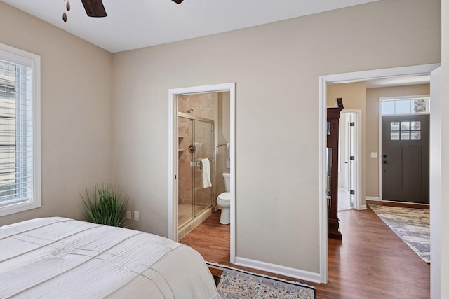 bedroom with wood finished floors, baseboards, ensuite bathroom, and ceiling fan